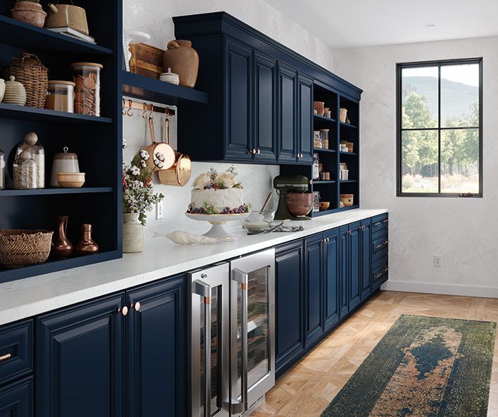 Navy blue kitchen with white countertops and open shelving.  Stainless steel wine fridge.