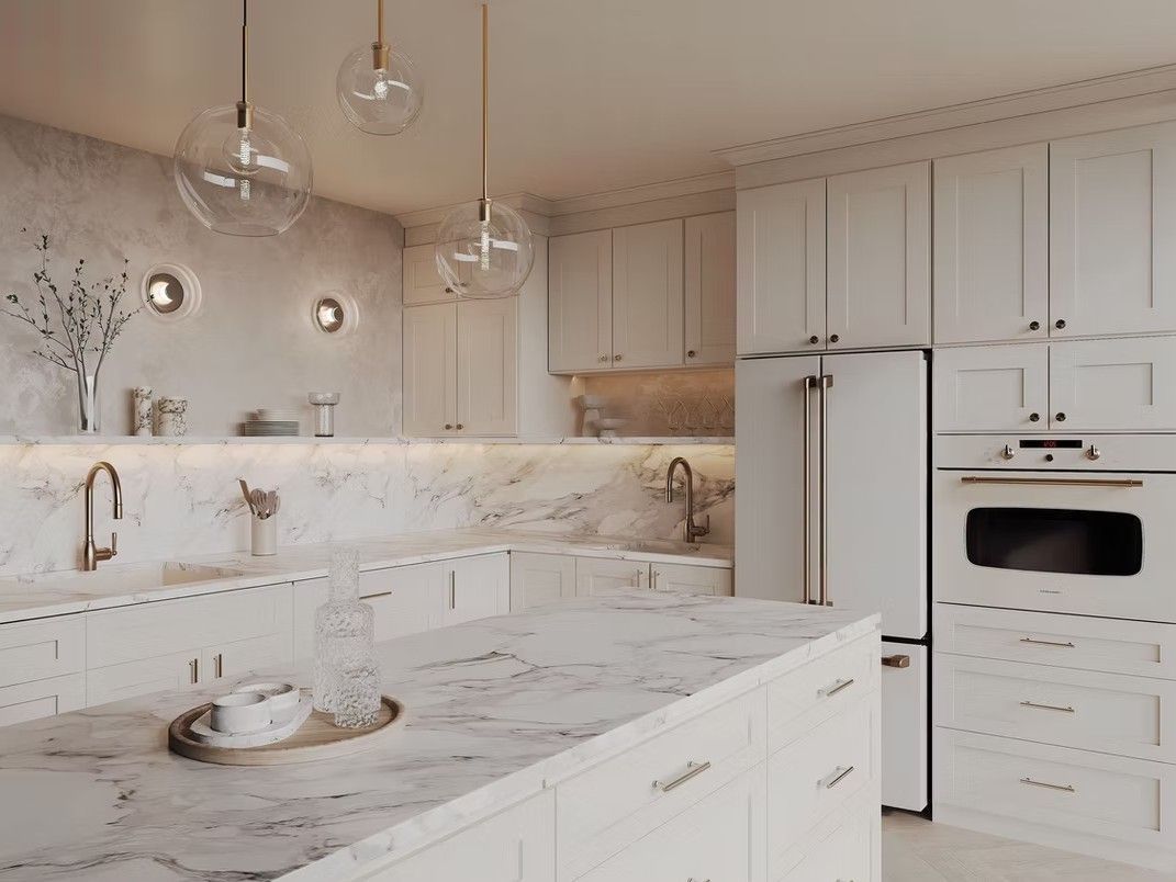 White kitchen with marble countertops, gold fixtures, and globe pendant lights.