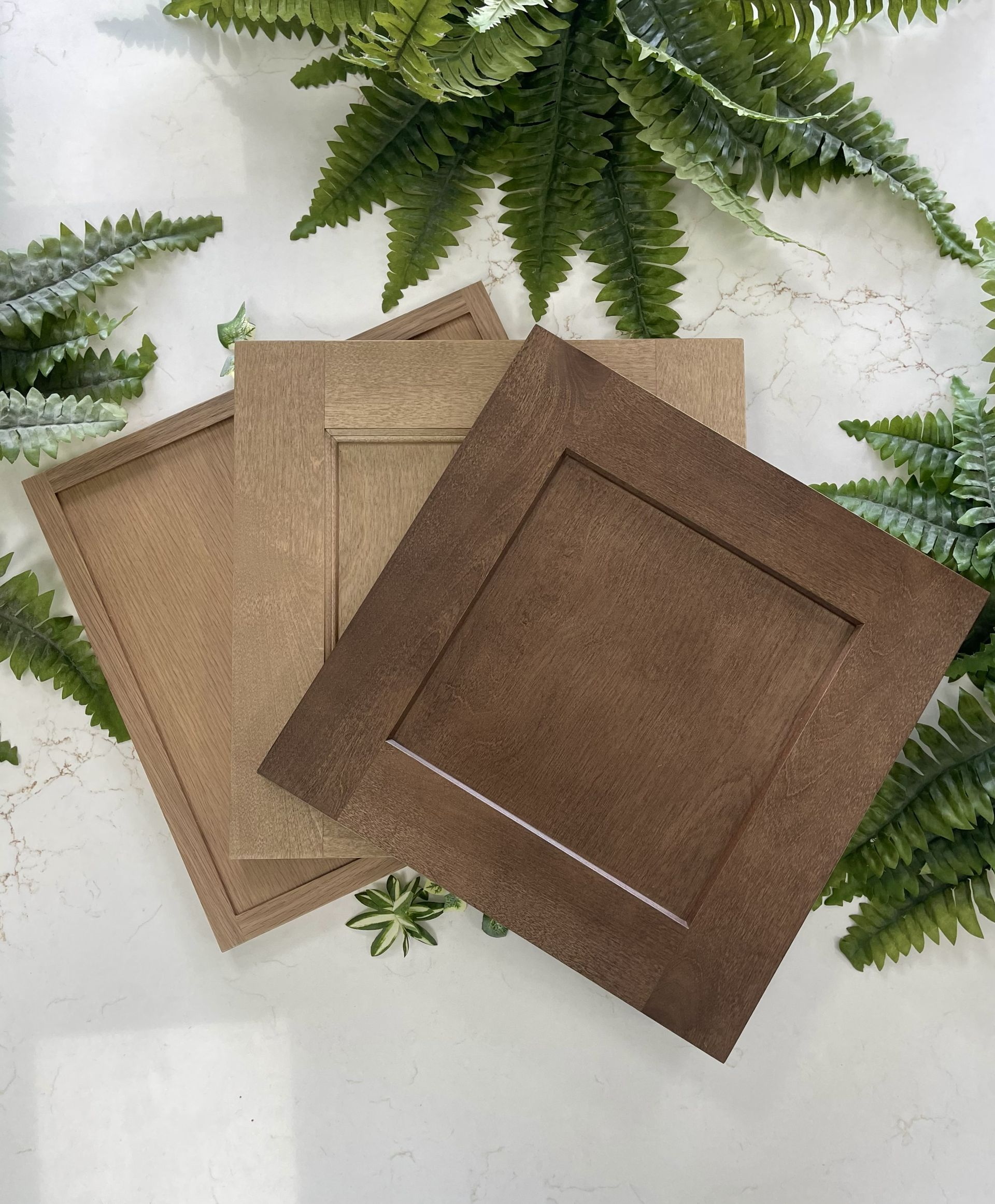 Three square, textured coasters in shades of tan, beige, and dark brown, arranged overlapping on a white background.