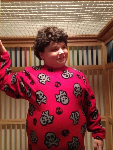 A boy wearing a red sweater with skulls and crossbones on it