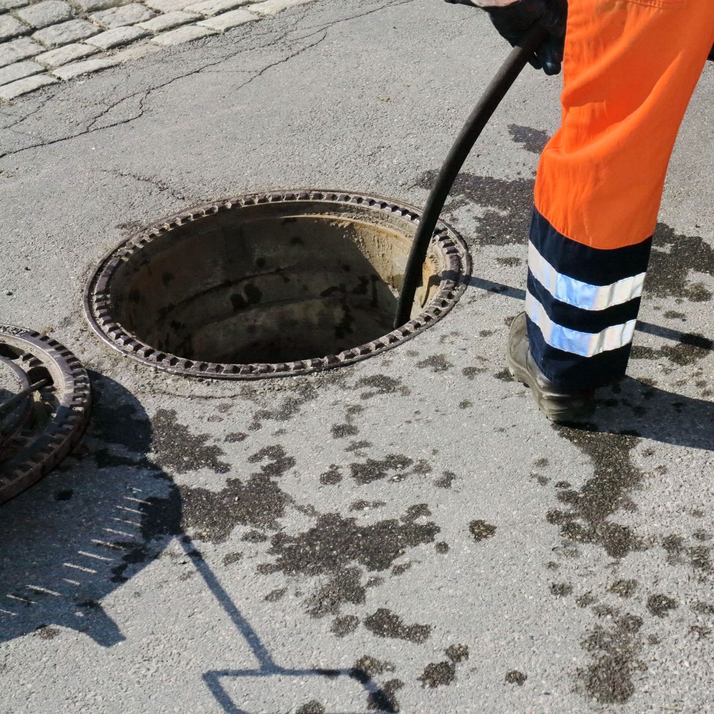 A green hose is being pumped into a septic tank.