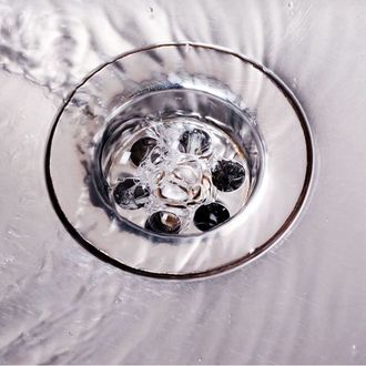 A close up of a sink drain with water running down it