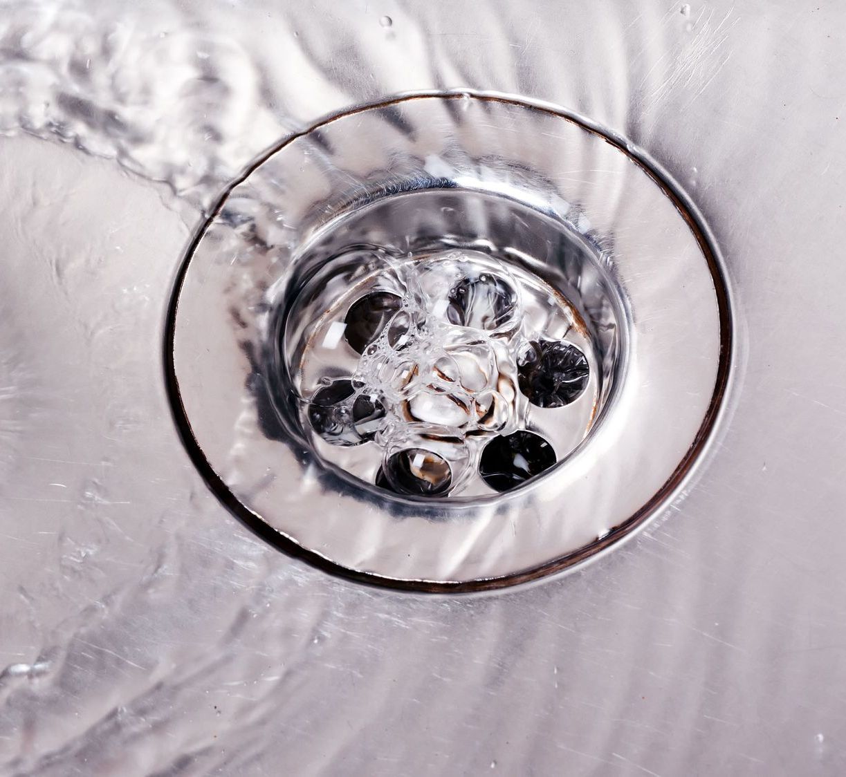 A close up of a sink drain with water coming out of it