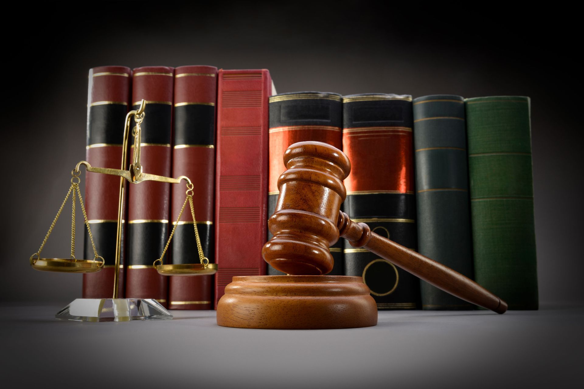 Law books with a judge’s gavel and scales of justice on a dark background