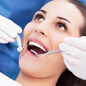 A woman is getting her teeth examined by a dentist.