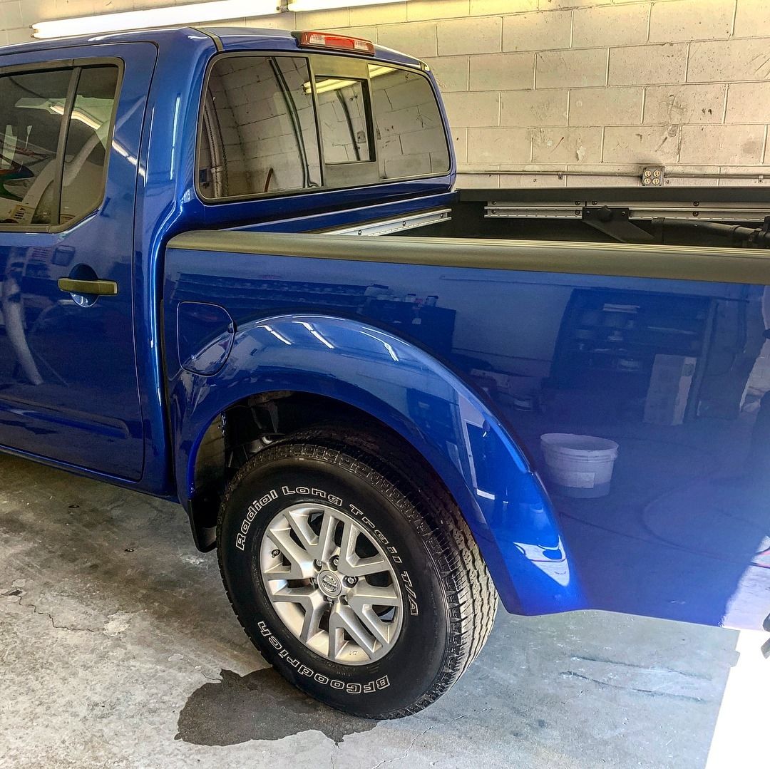 Blue pickup truck parked inside a building with a white brick wall.