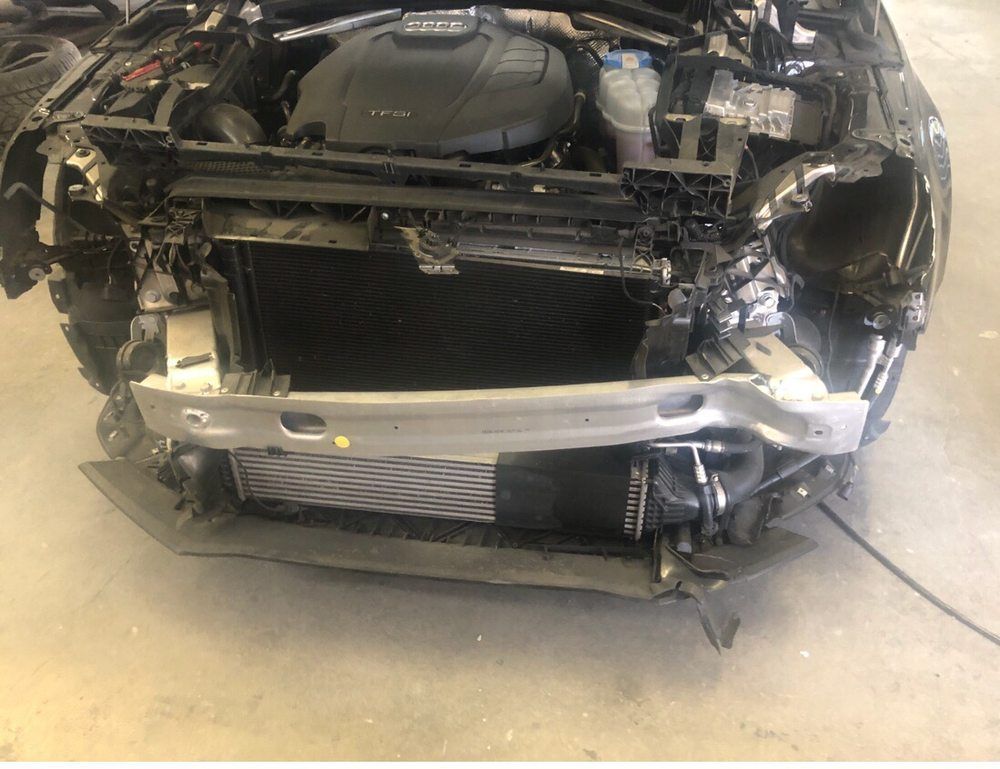 Front end of a damaged black car, impact visible. Radiator and engine bay exposed.