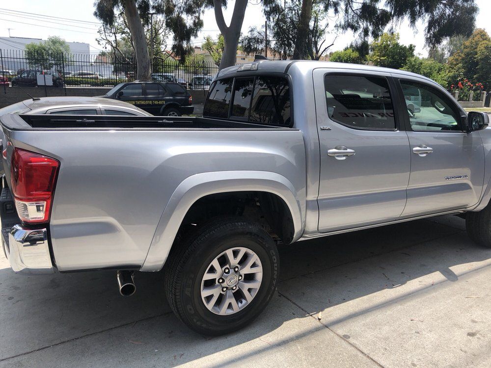 Silver Toyota Tacoma pickup truck parked on a sunny street.
