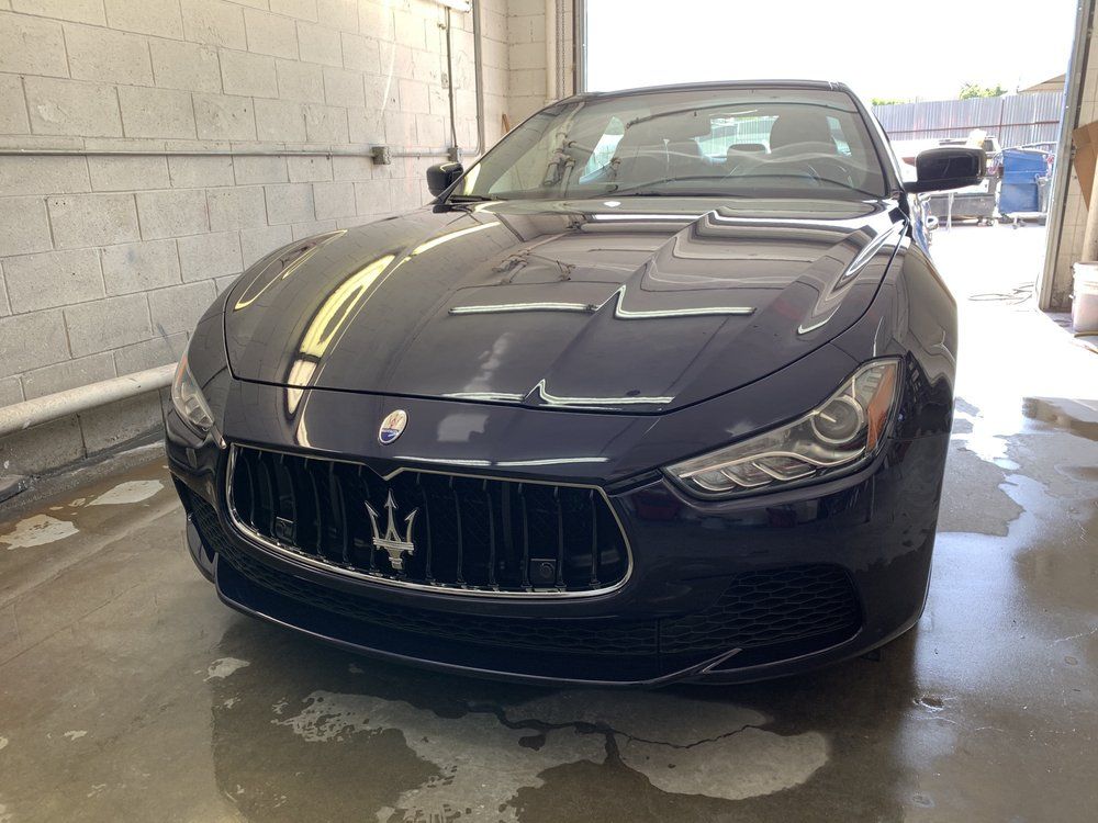 Dark blue Maserati Ghibli sedan in a car wash, front view.
