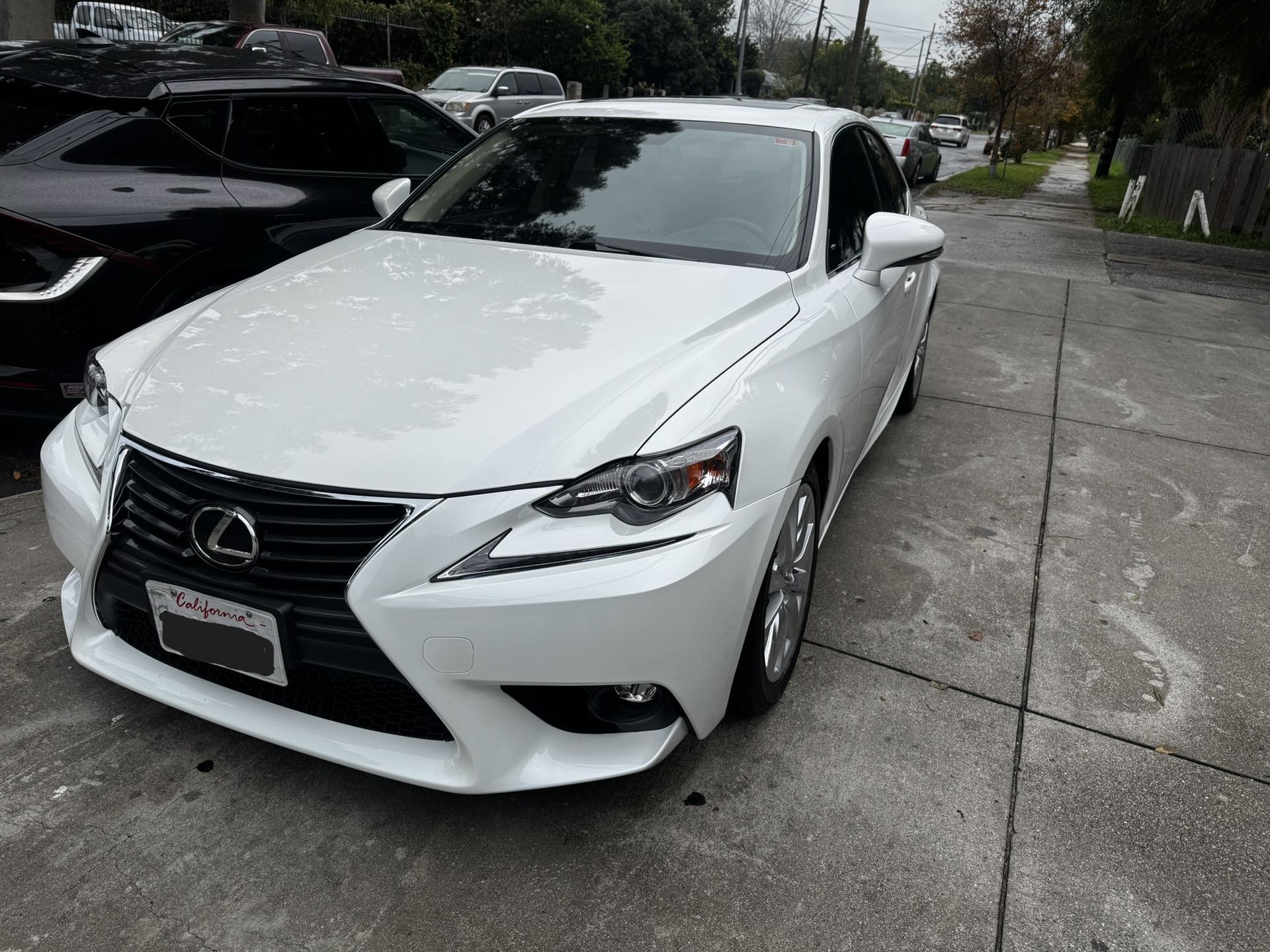 White Lexus sedan parked on a gray paved street.
