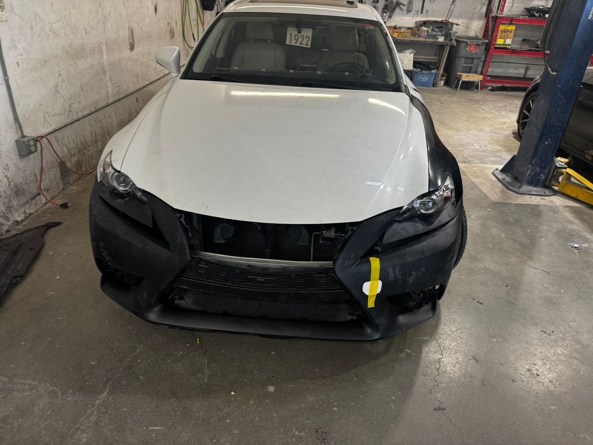White car with black front end cover in a garage.