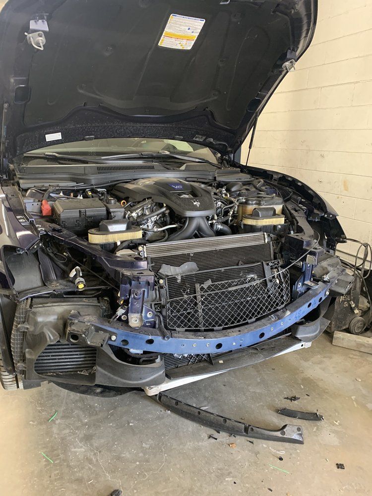 Damaged blue car with open hood, showing front end damage.