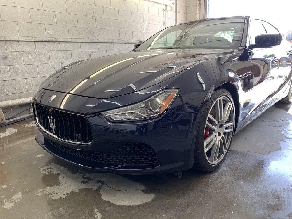 Dark blue Maserati sports car parked indoors on wet concrete.