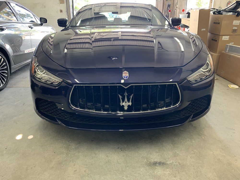 Dark blue Maserati car, front view, inside a garage.