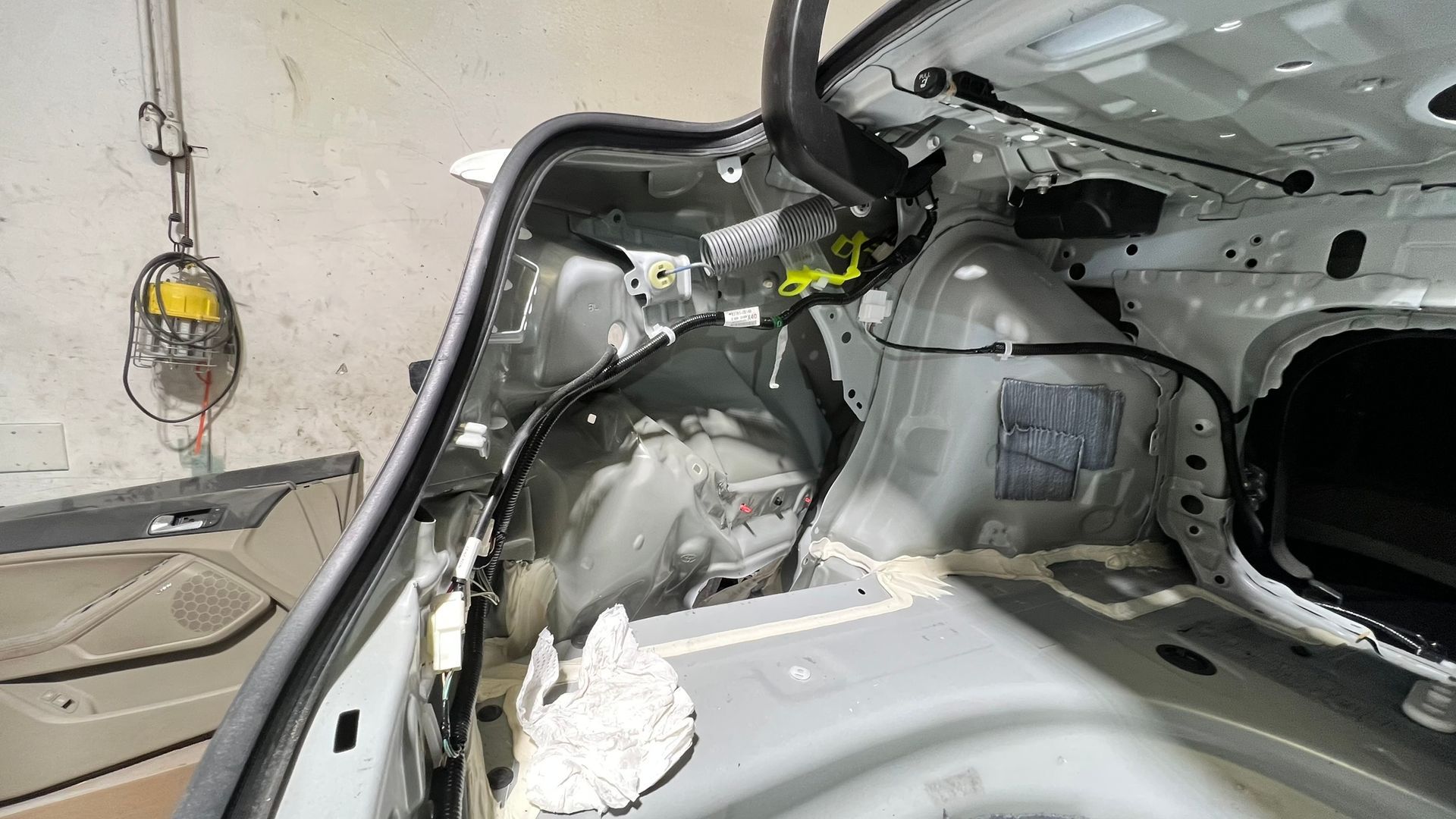 Interior car trunk with exposed metal frame, wiring, and insulation.