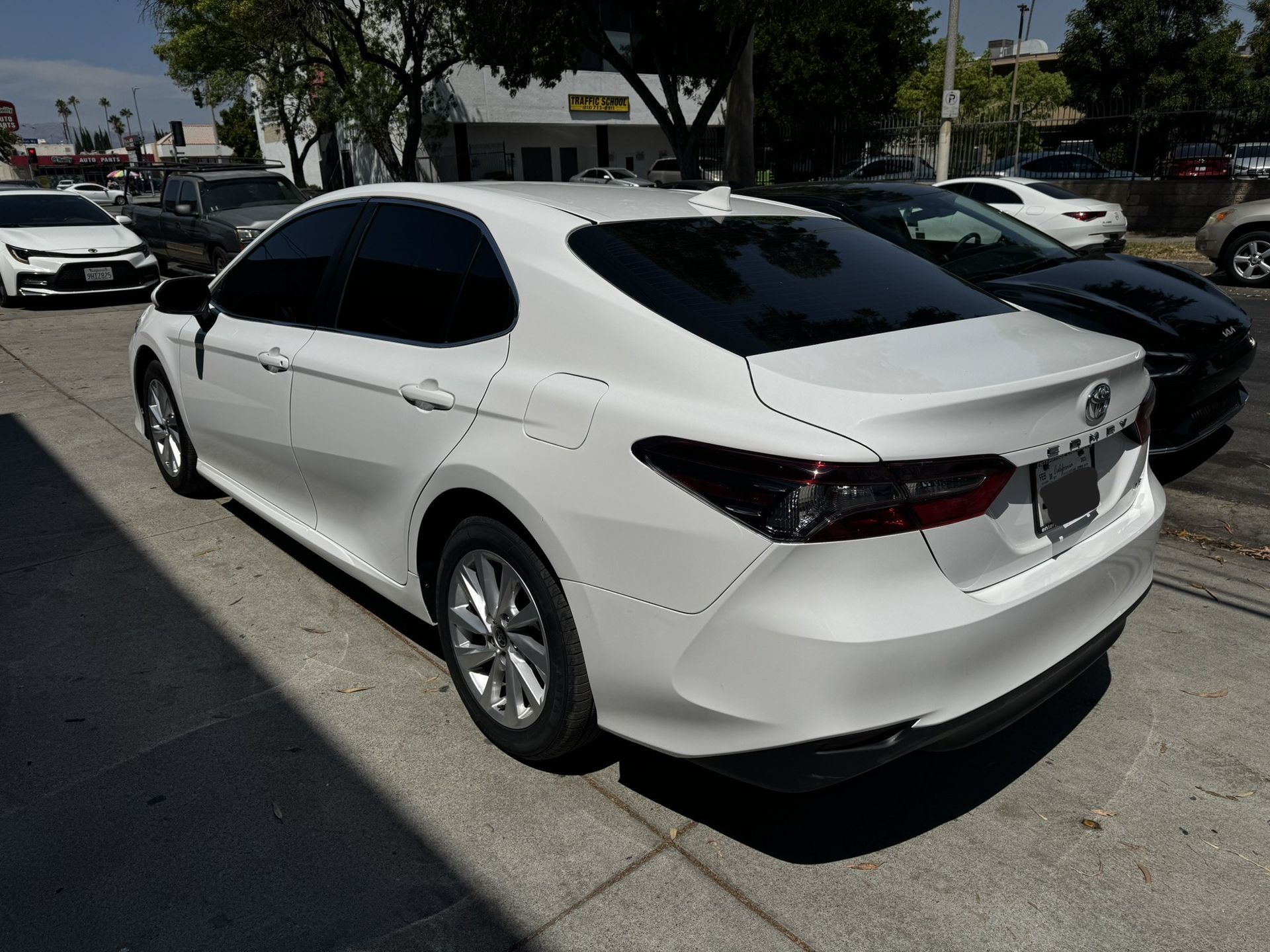 White Toyota Camry sedan parked on a city street, daytime.