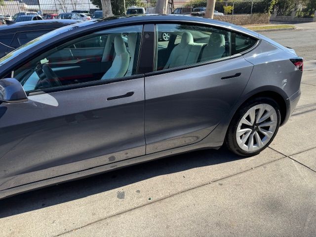 Gray Tesla sedan parked outside, with light-colored interior visible.