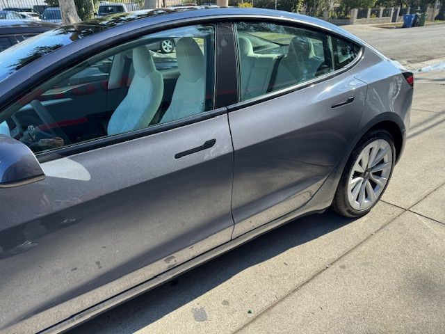 Gray Tesla car parked on a street with white interior and a black roof.