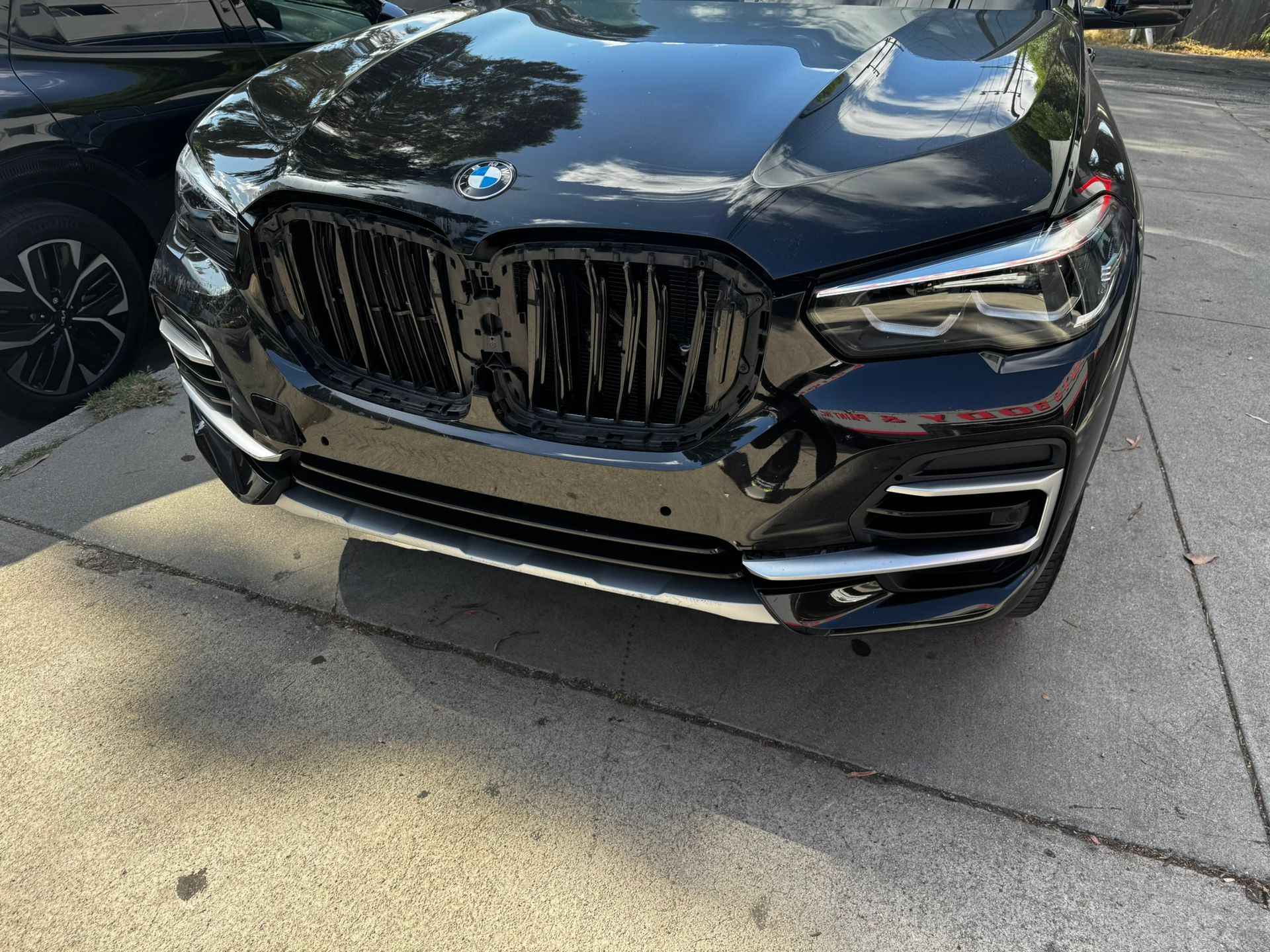 Black BMW SUV parked on pavement, front view, shiny finish, chrome accents.