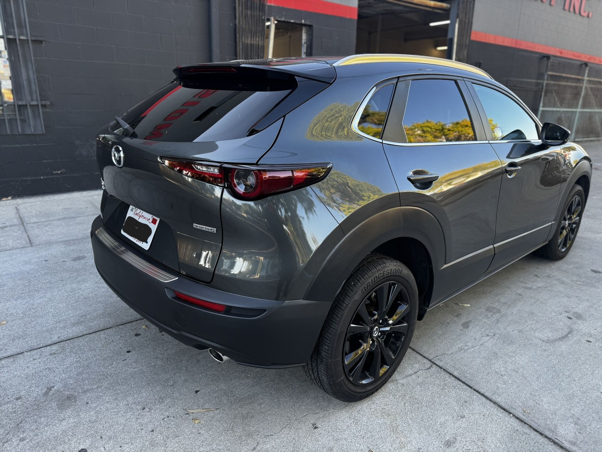 Dark gray Mazda CX-30 SUV parked outside, black wheels, tinted windows, and black trim.