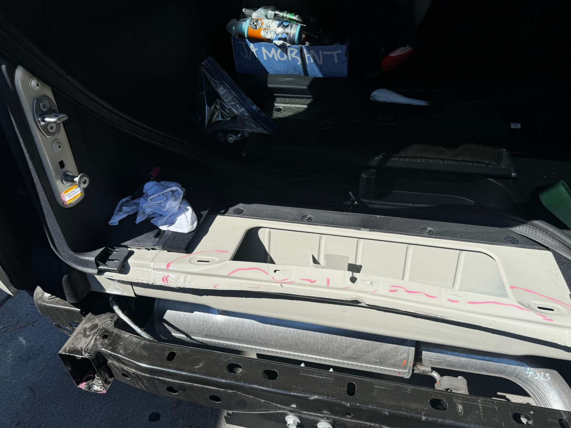 Open car trunk interior, showing the frame, bumper, and contents. Some objects are visible inside.