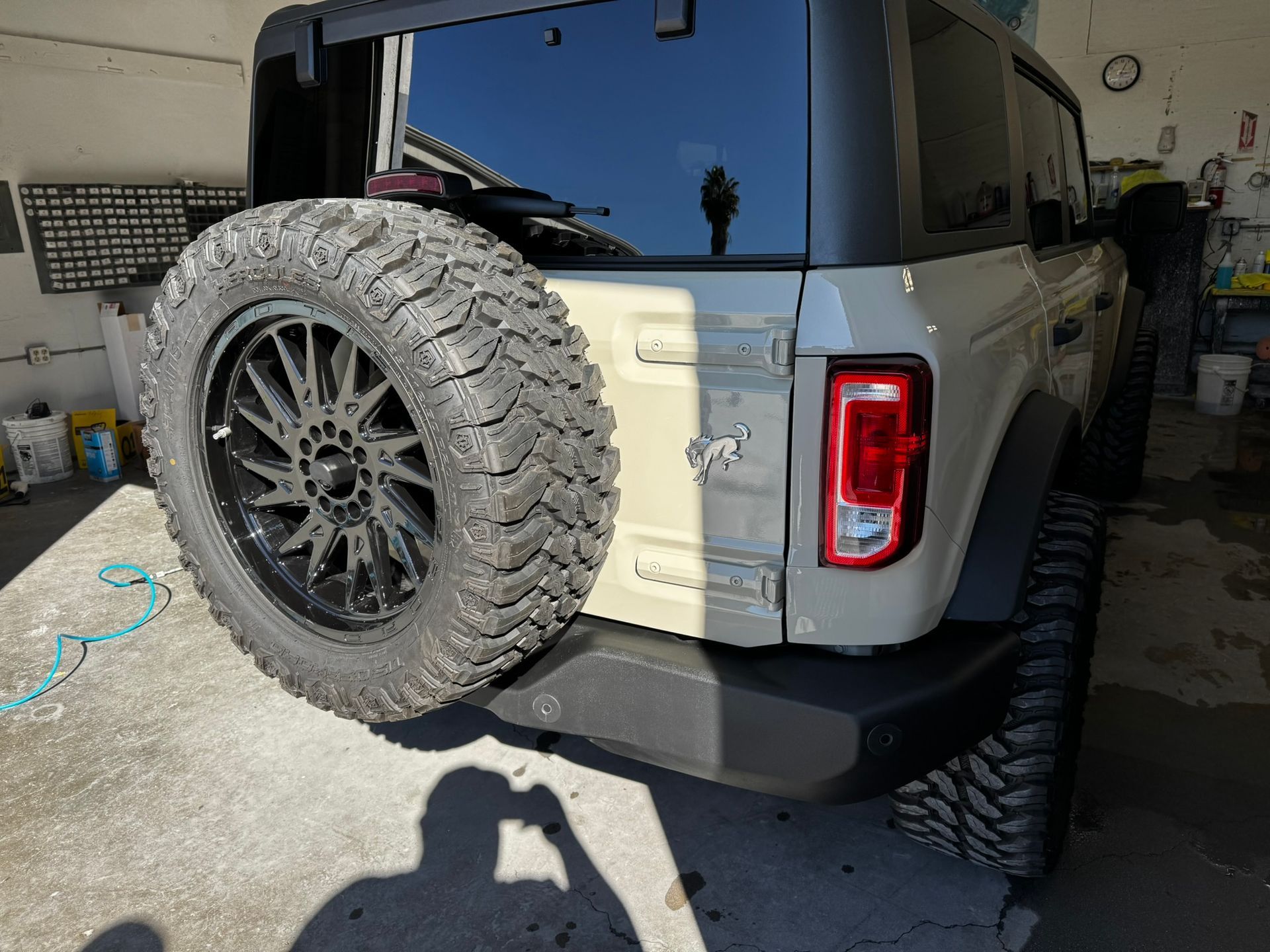 Tan Ford Bronco SUV with spare tire, parked inside a garage.