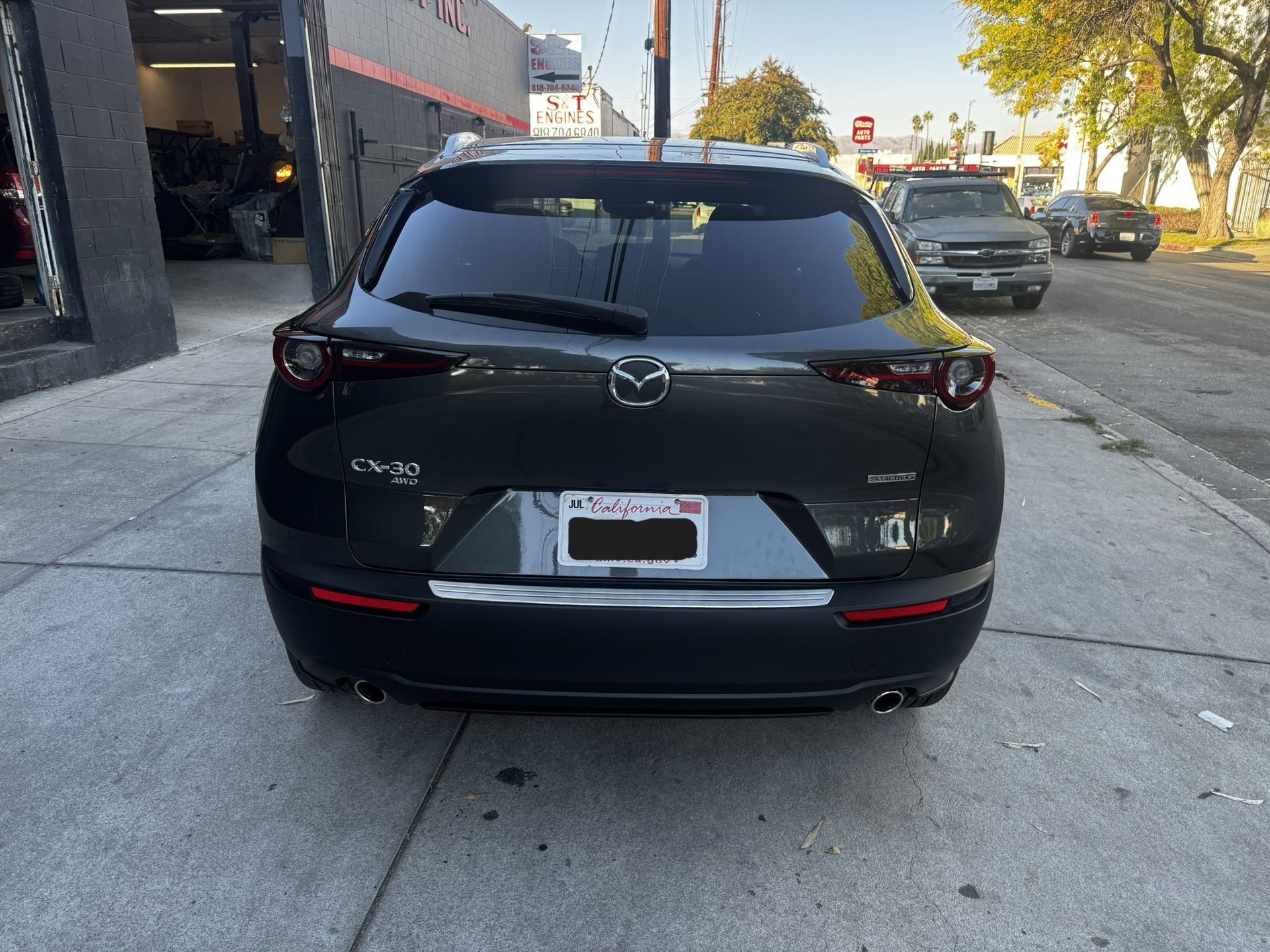 Dark gray Mazda CX-30 SUV parked on a city street, rear view, California license plate.