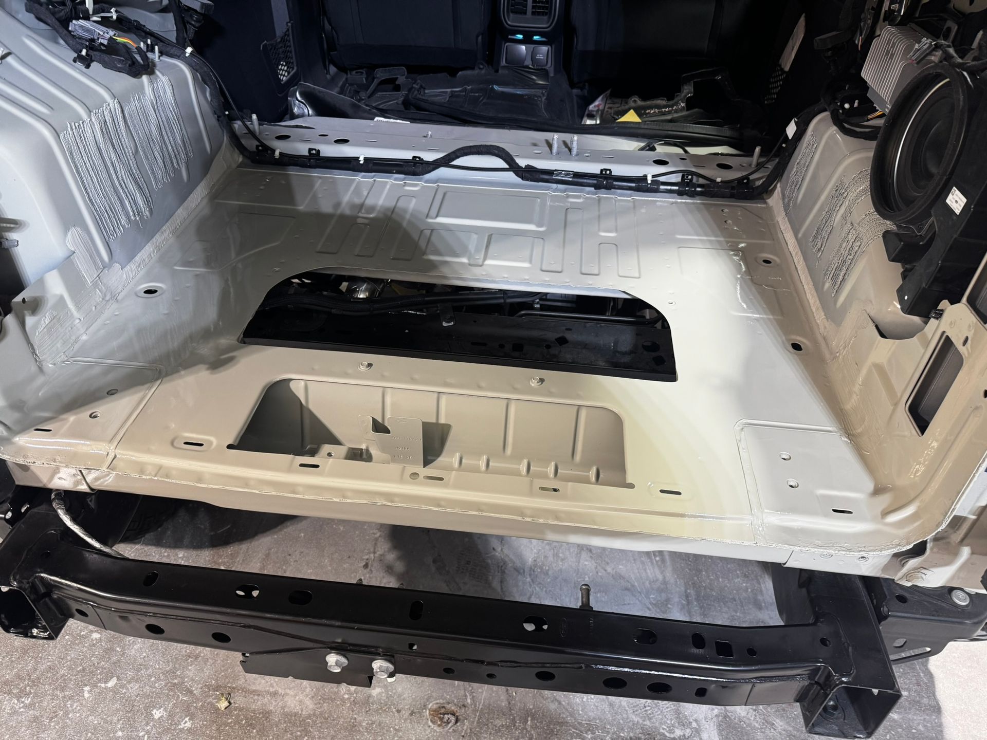 Empty car interior showing the trunk area; white and black frame, metal base.