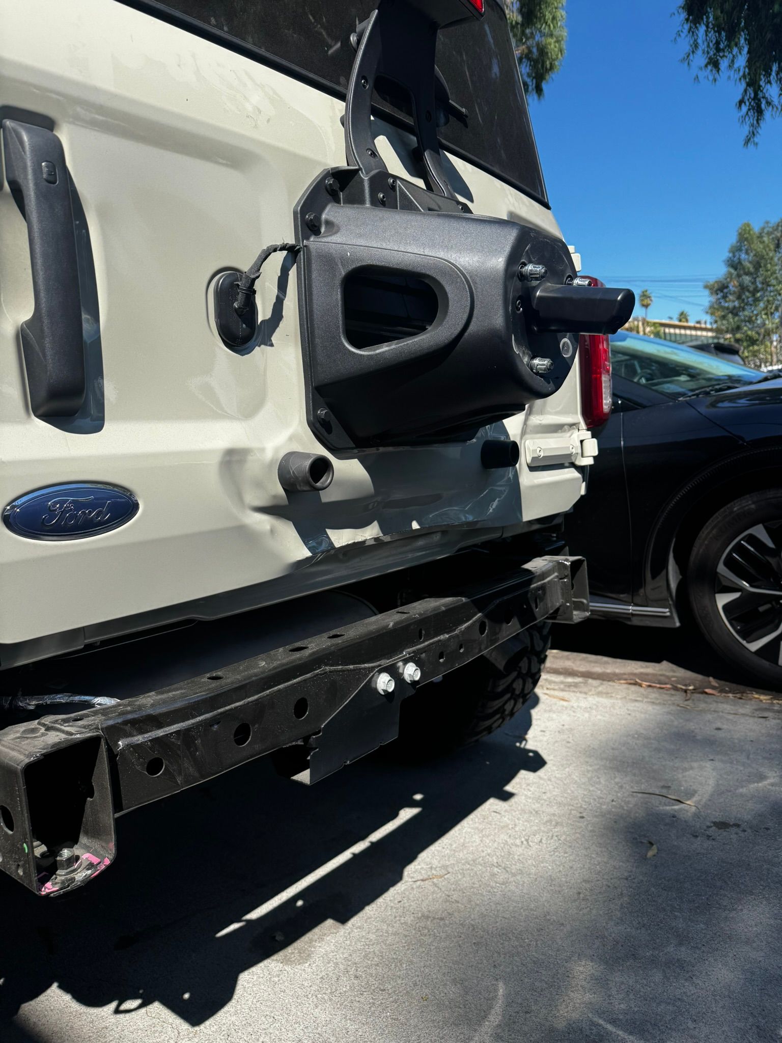 White SUV with black aftermarket bumper and spare tire carrier, parked outdoors.