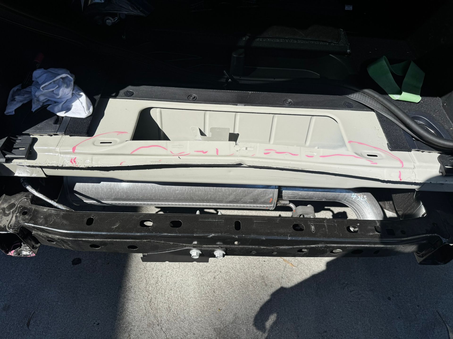 Car trunk interior with gray metal frame; red markings indicate repair areas.
