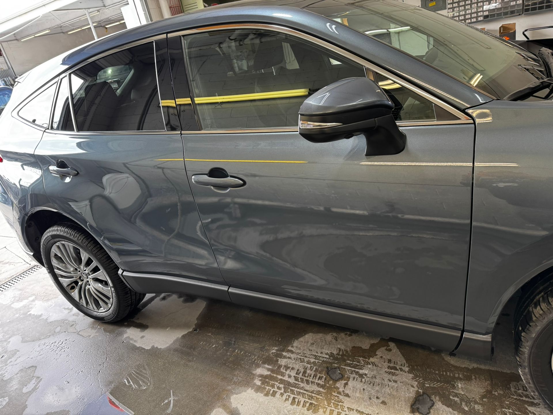 Gray car parked outside, angled view, showing side and front. Reflective surface.