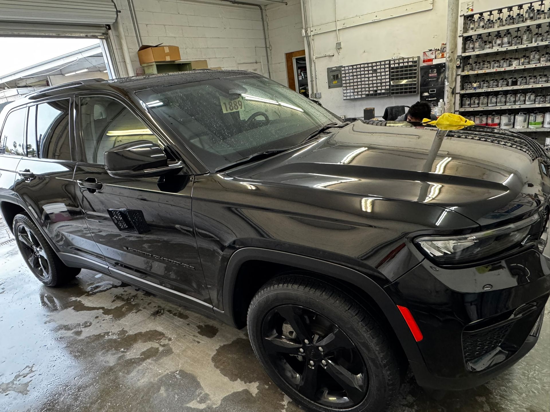 Black Jeep Grand Cherokee in a garage, shiny paint, black rims.