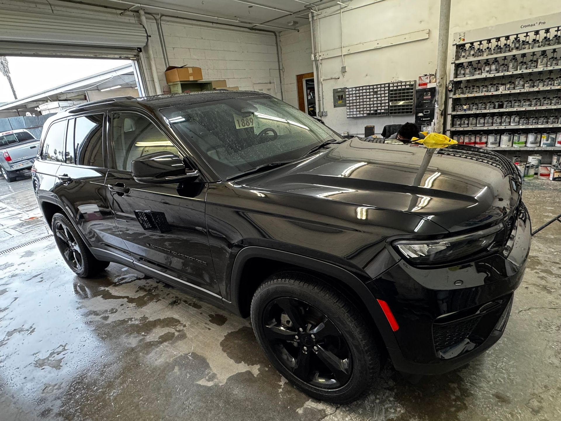 Black SUV parked inside a garage; wet floor reflects the vehicle and surrounding.