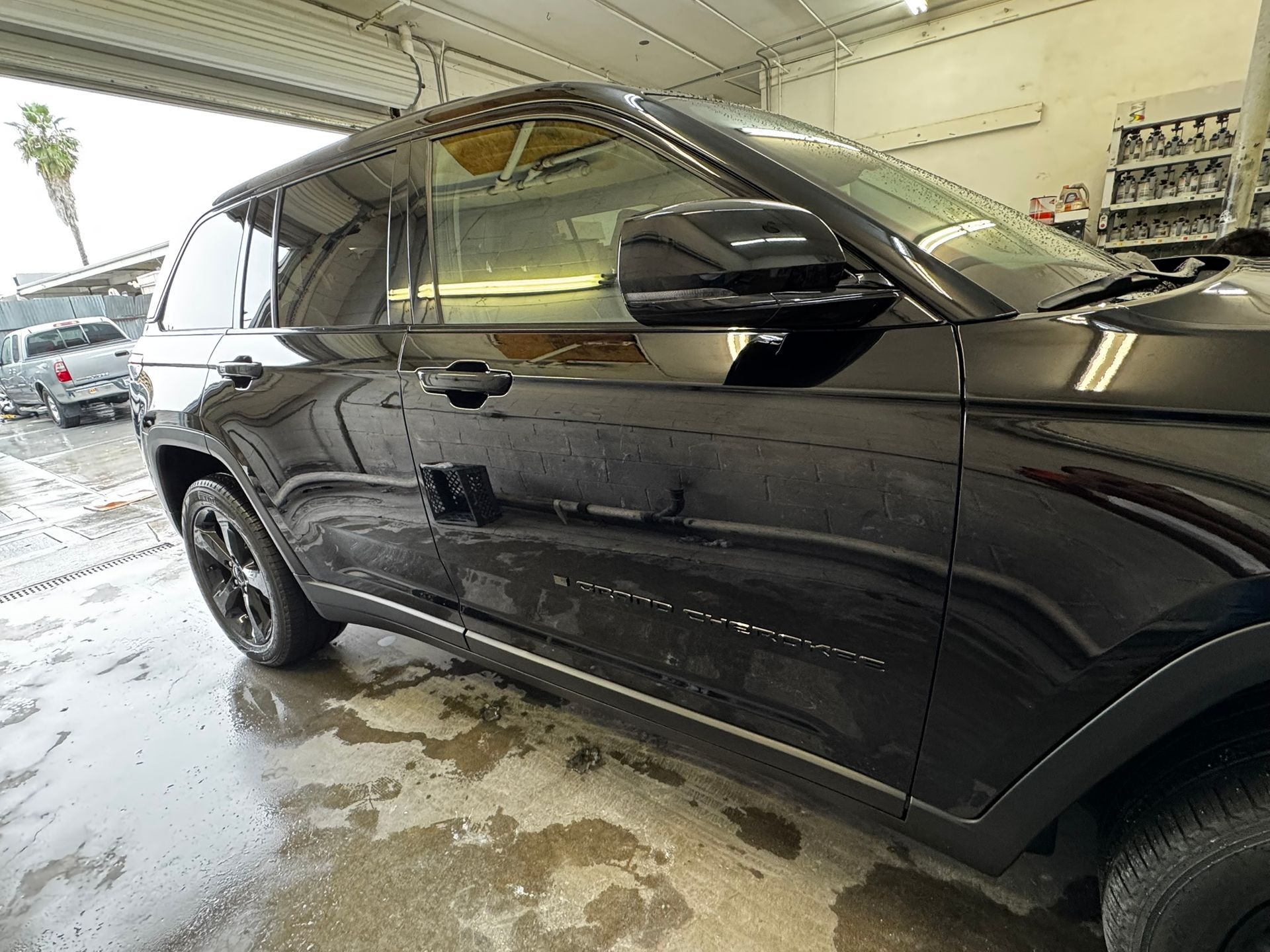 Black SUV parked in a car wash, wet with water.