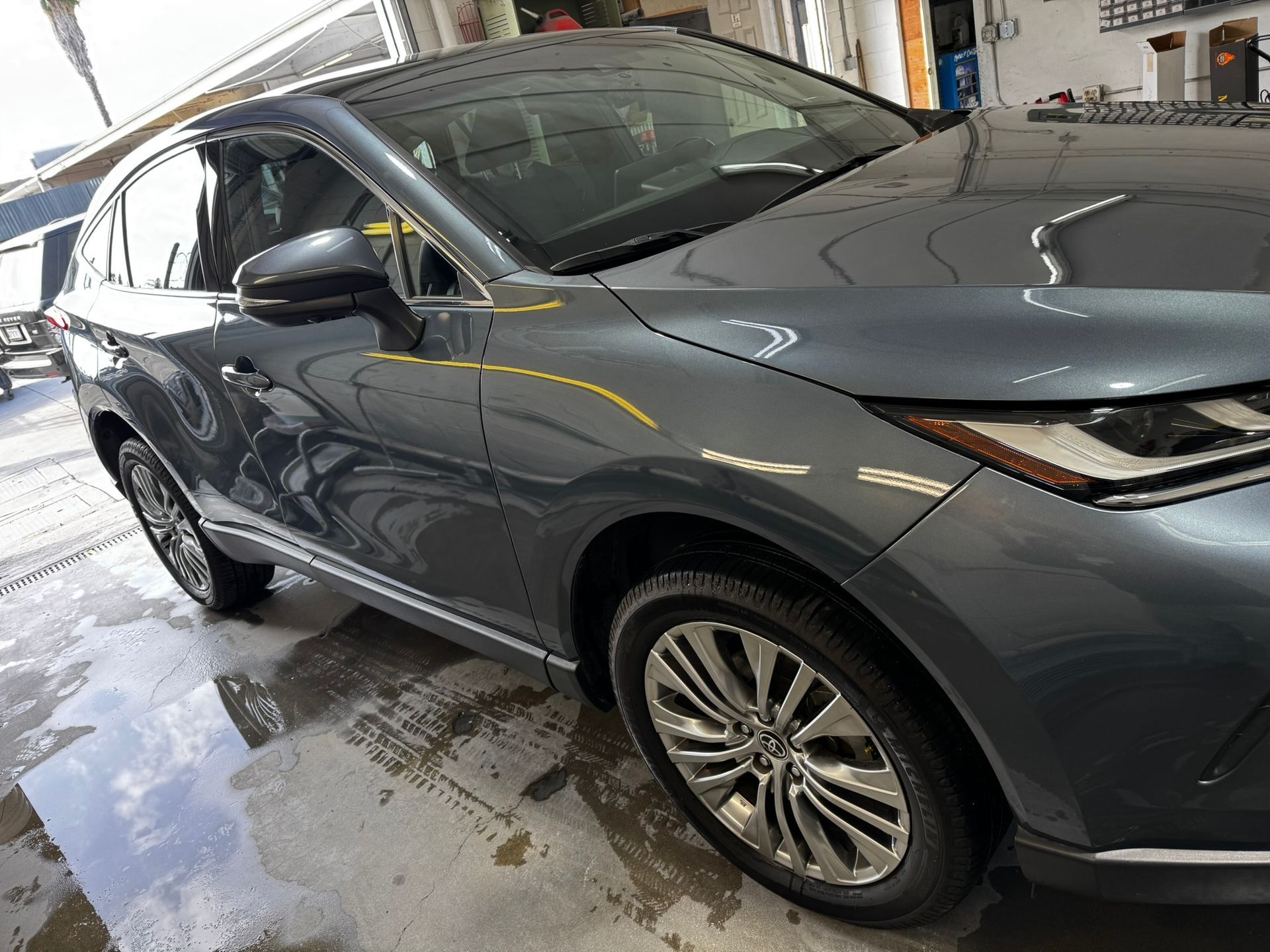 Gray Toyota Venza SUV parked inside, shiny paint, reflective wet floor, sunny day.