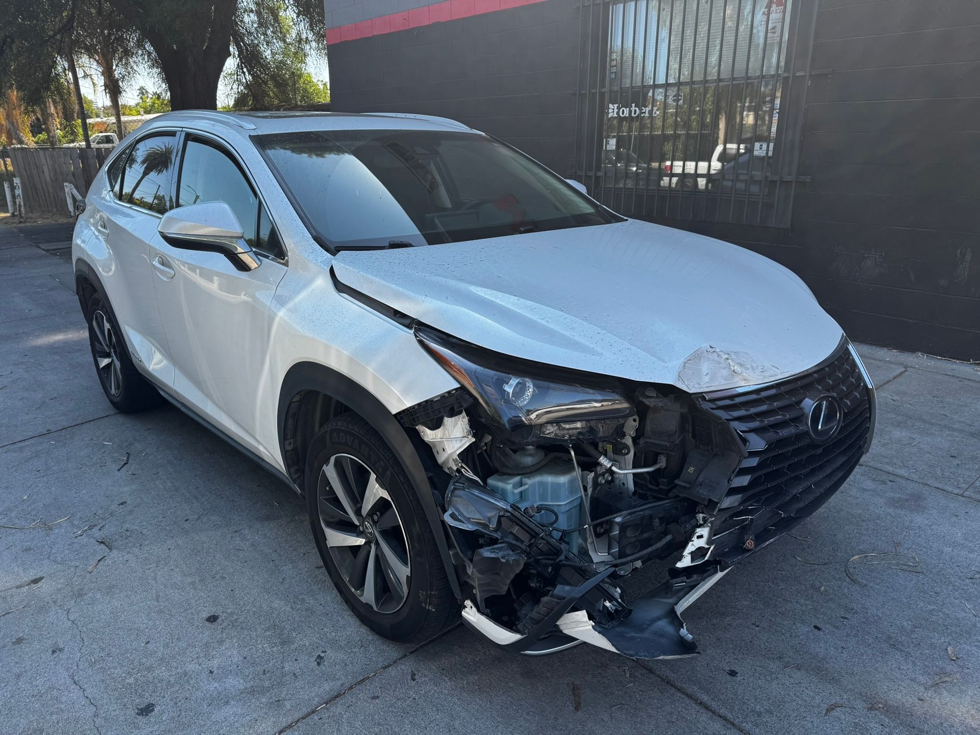 White Lexus SUV with severe front-end damage; parked on asphalt.