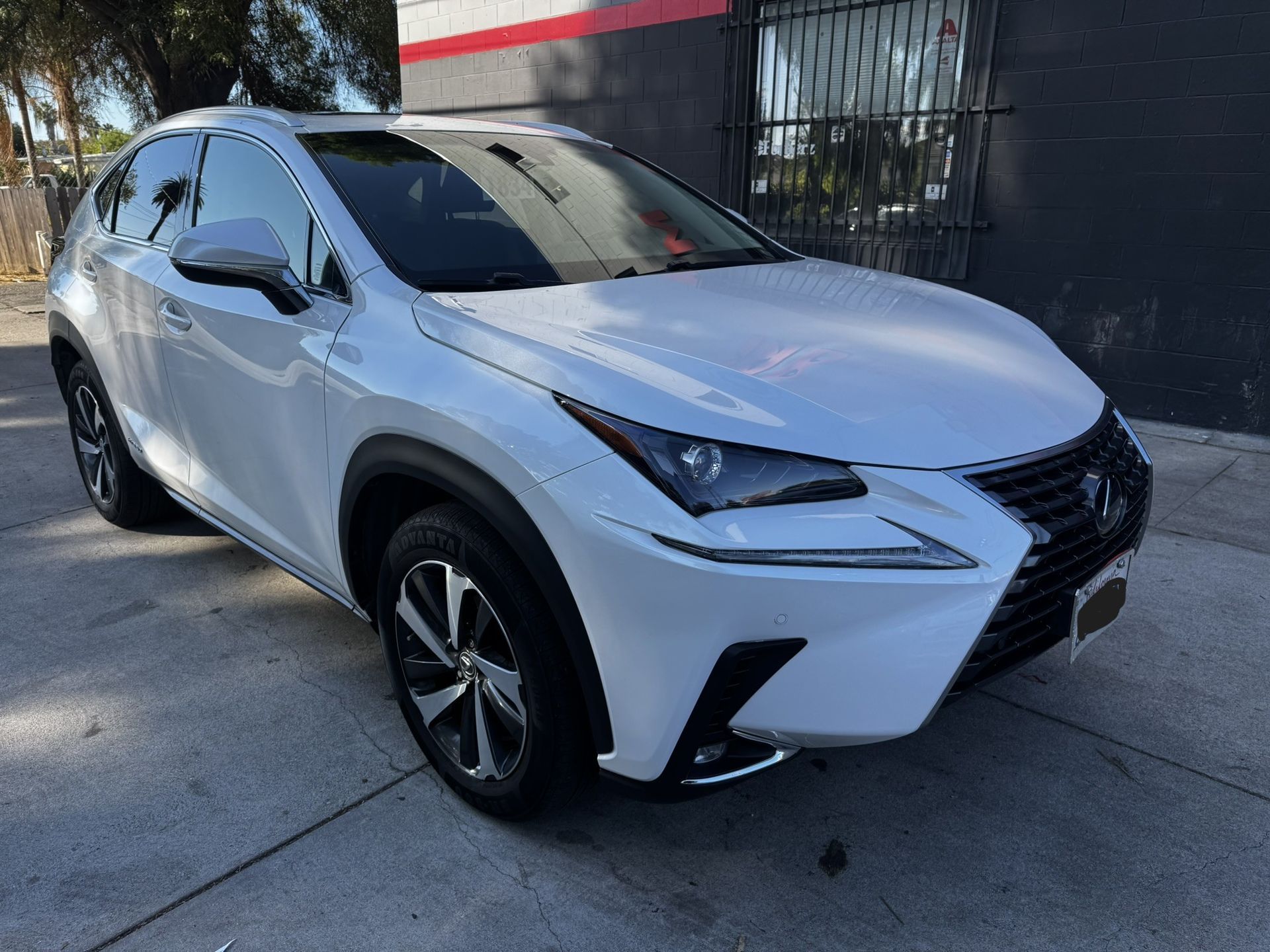 White Lexus SUV parked on a paved surface in front of a building.