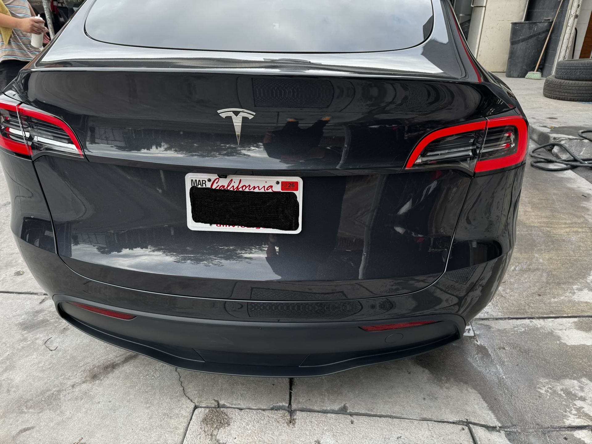 Rear view of a dark gray Tesla with California license plate.