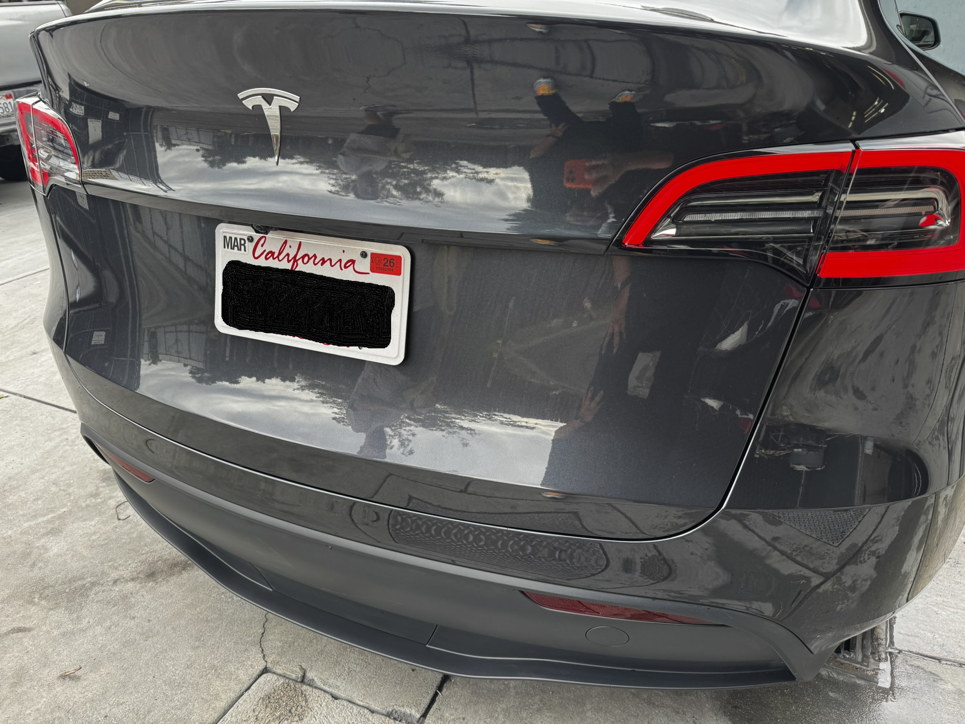 Rear view of a dark gray Tesla Model 3 with a California license plate.