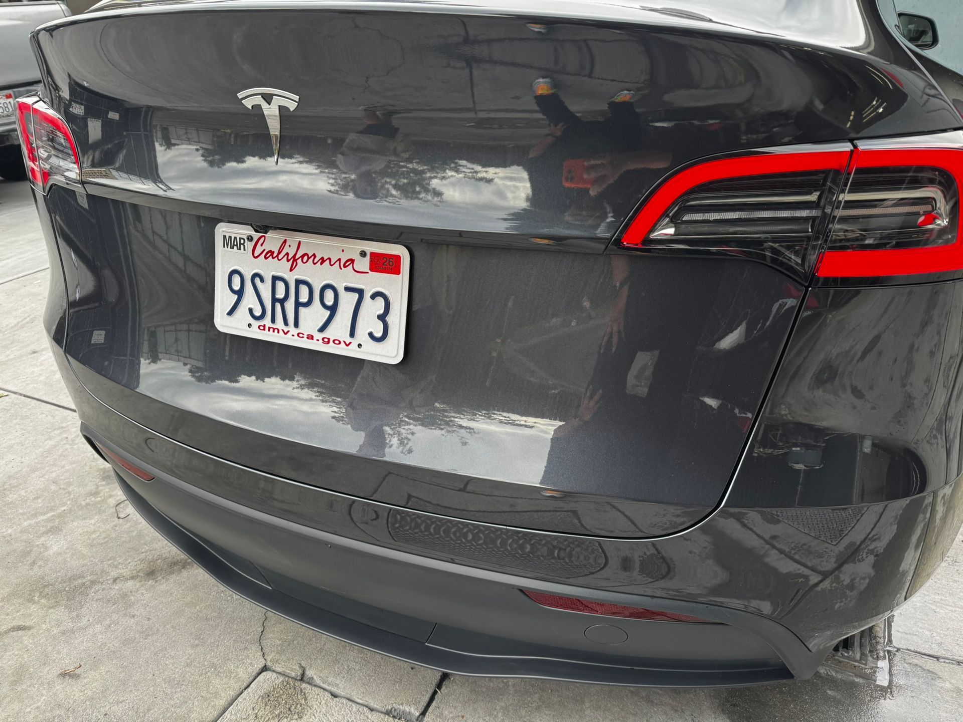 Rear view of a dark gray Tesla Model 3 with a California license plate: 9SRP973.