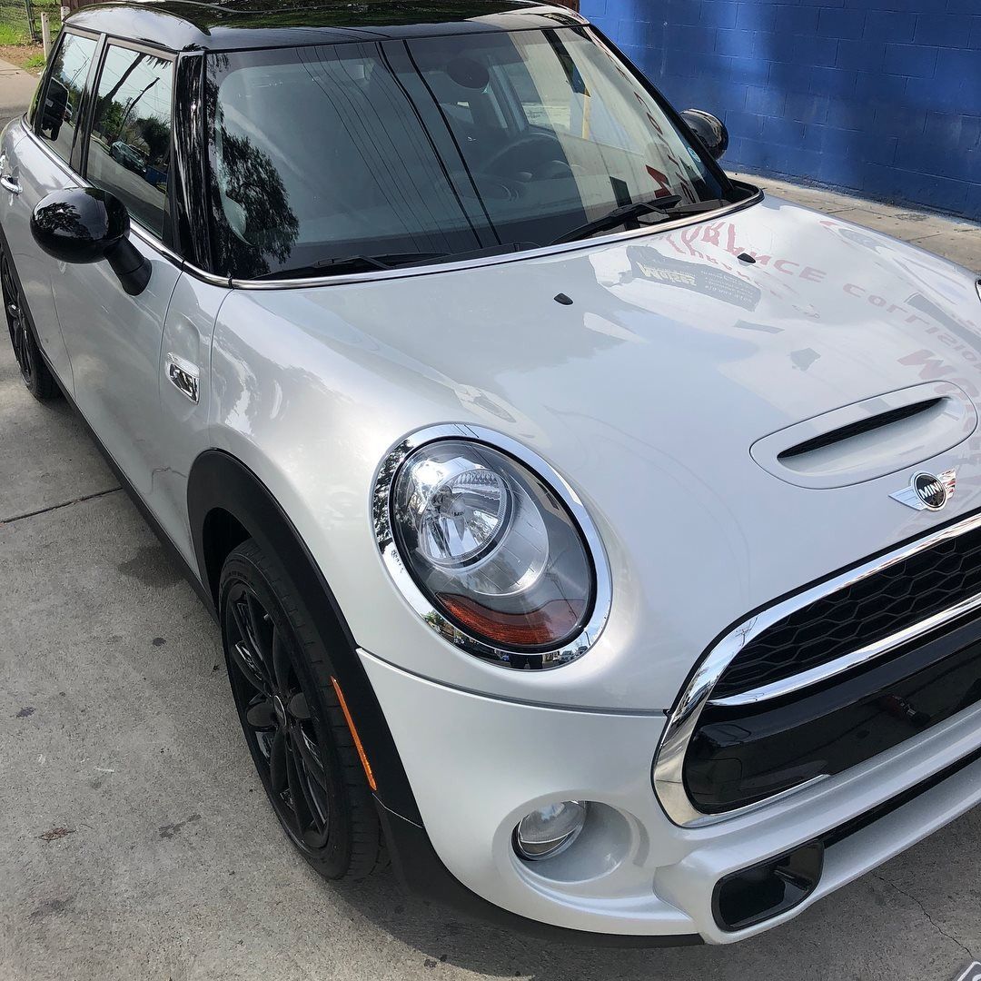 White Mini Cooper with black accents parked on pavement.