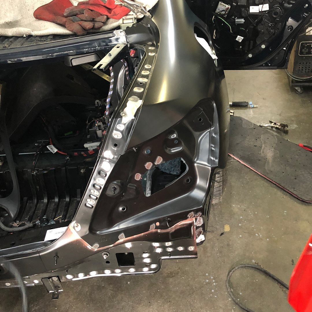 Car body repair: new panel welded to rear frame. Metal parts in a workshop.