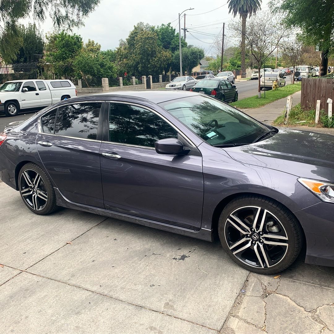 Gray sedan parked on a street with tinted windows and black and silver wheels.