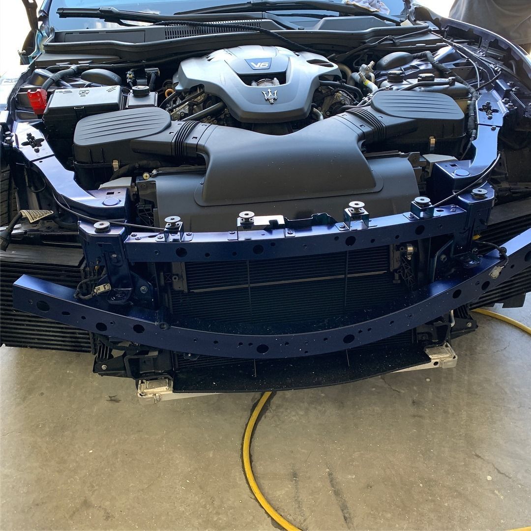 Blue car engine bay with front bumper removed.