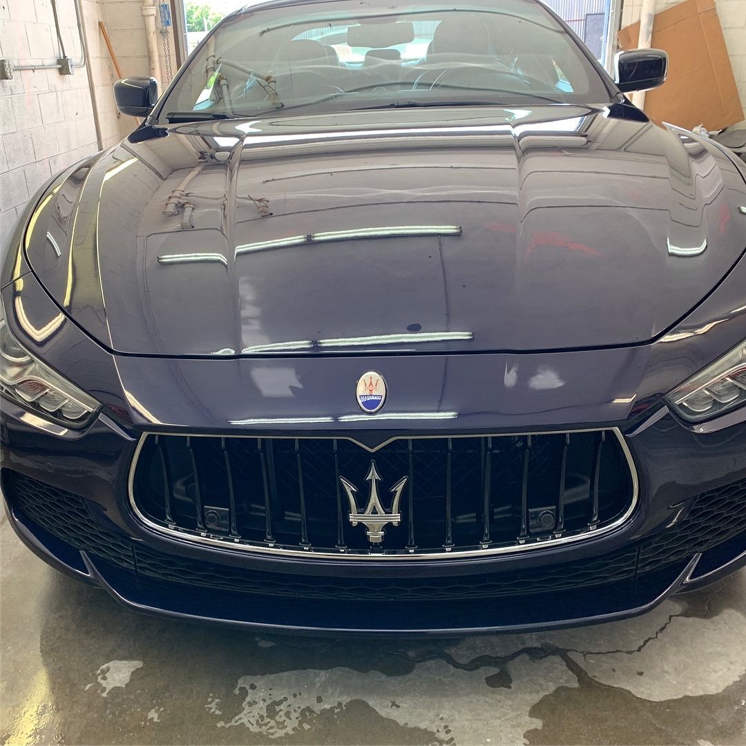 Dark blue Maserati sports car, front view, in a garage.