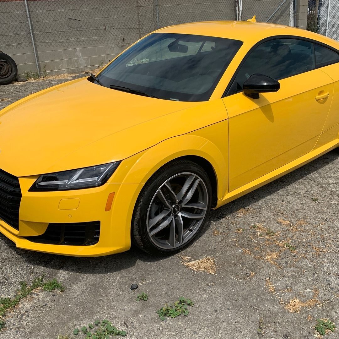 Yellow Audi TT coupe parked outside.