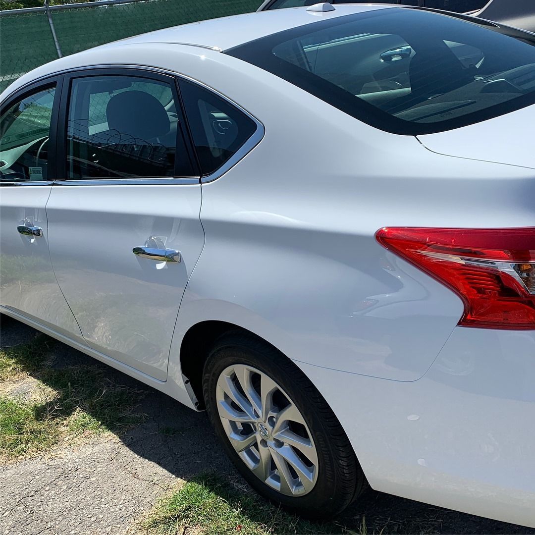 White Nissan Sentra sedan parked outdoors, side view.