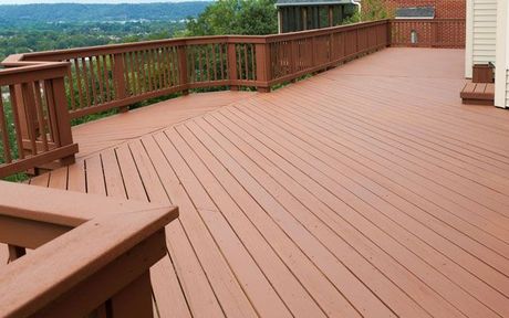 Custom Decks Wooden deck with brown railing overlooking a scenic green landscape