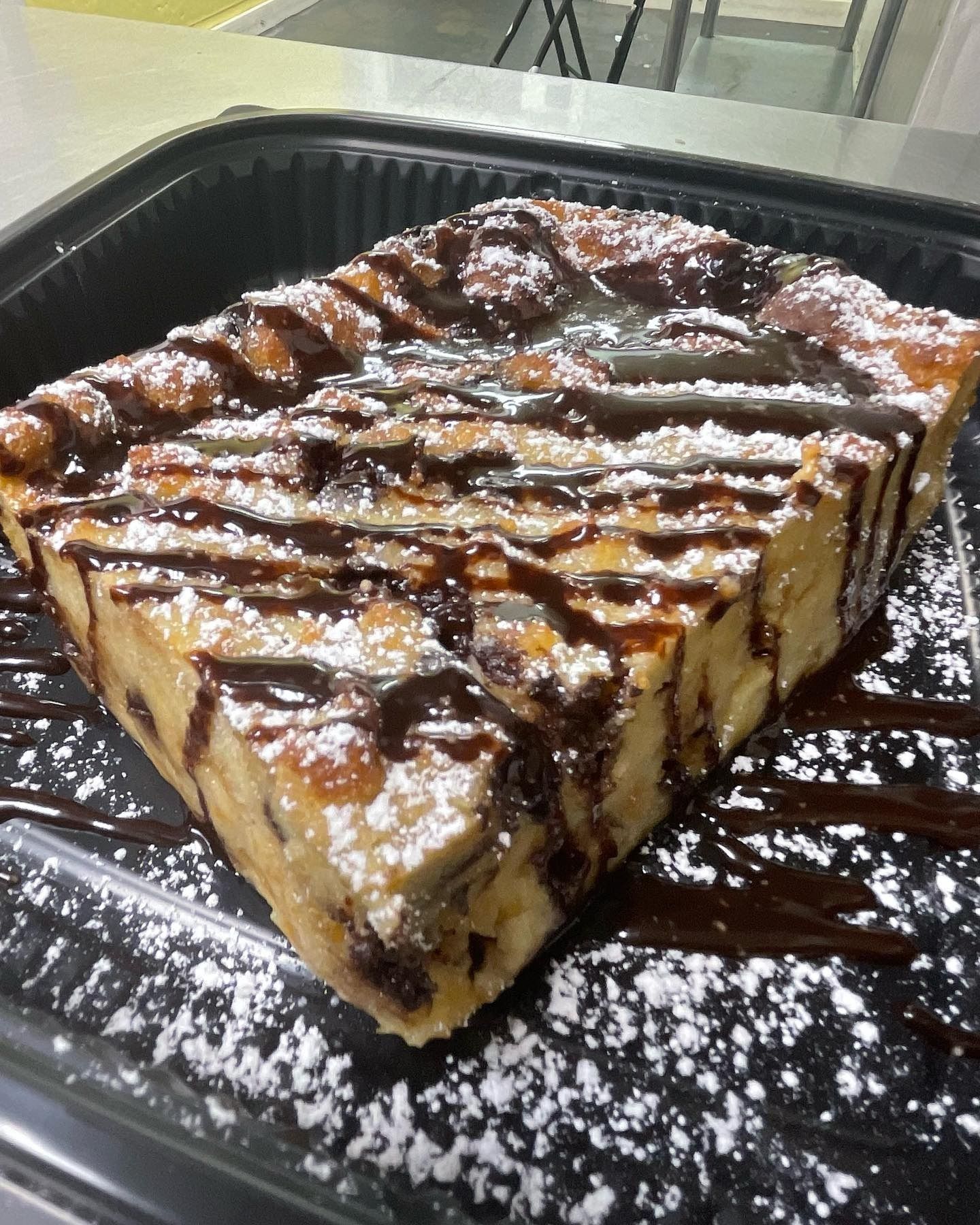 A piece of cake with chocolate sauce and powdered sugar on a tray.