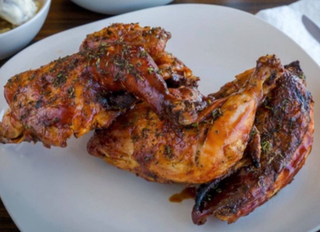 A white plate topped with grilled chicken on a wooden table.